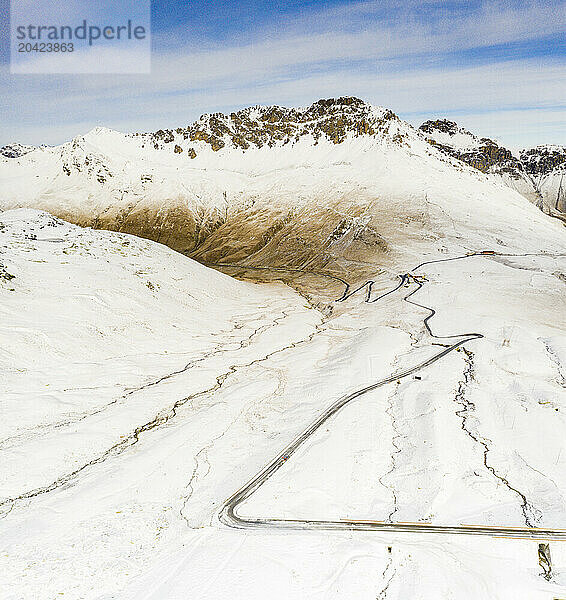 Aerial view of a winding snowy road of a mountain pass  Valtellina