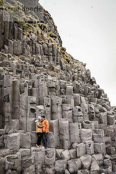 Couple kissing amidst towering basalt columns in Iceland