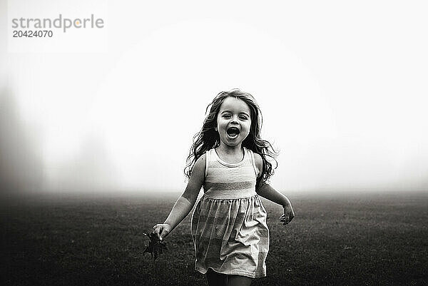 Happy little girl running with leaf in hand