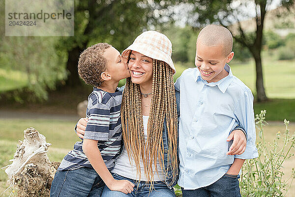 Brother kissing sister on the cheek while hugging each other