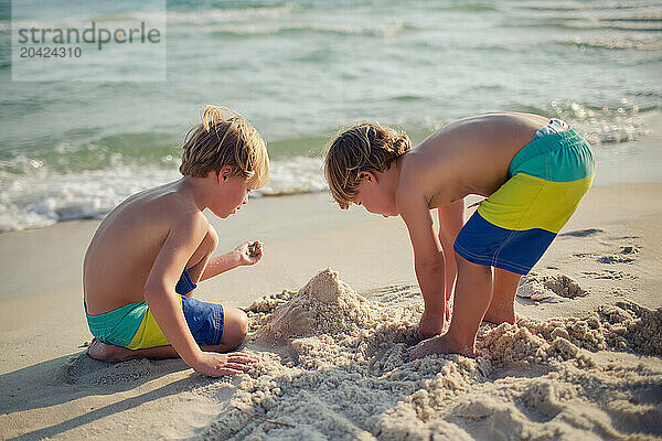 Young brothers building a sandcastle on a bright beach