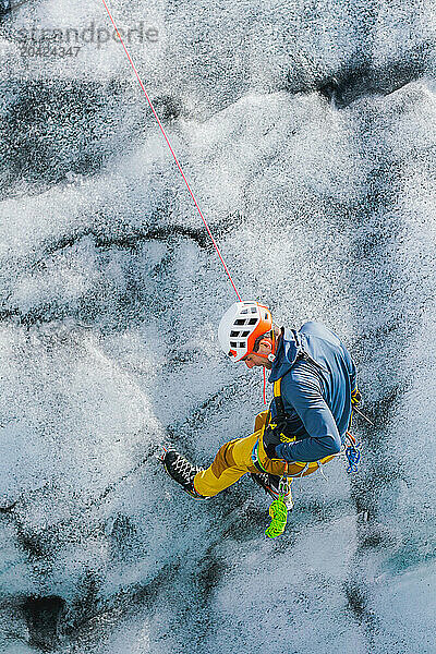 A young man descents down a crevasse on an Icelandic glacier