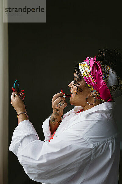 Beautiful black woman applying lipstick