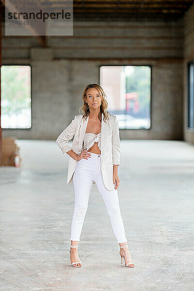 Confident woman in white suit standing in warehouse