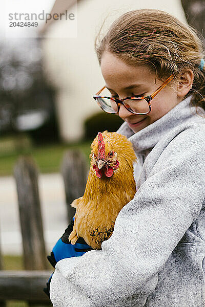 Blond tween girl with glasses holds a golden brown chicken