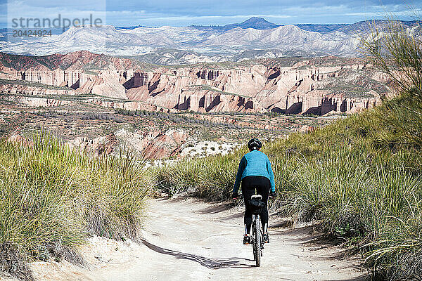 Cyclist woman riding into desert canyon.