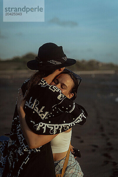 Friendly hugs of two women on the beach by the ocean.