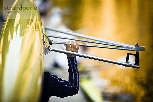 A young man carries a rowing shell over his head.