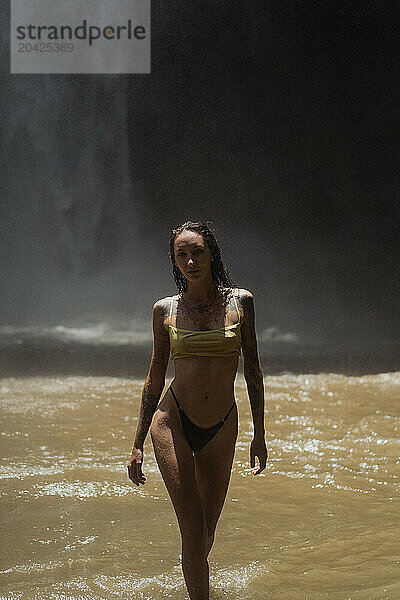 Woman enjoying under waterfall flowing over rock formation