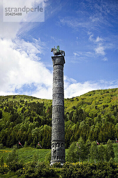 A carved stone pillar stands in a field in Central Norway.