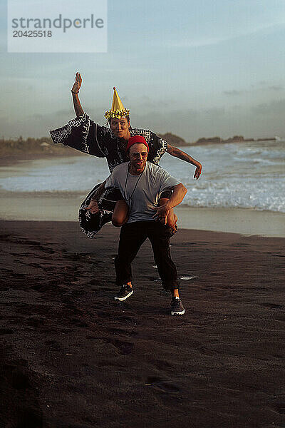 Happy friends fooling around on the beach at party.