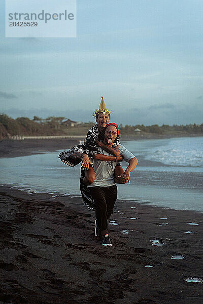 Happy friends fooling around on the beach at party.