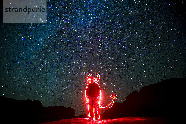 A man uses a flashlight to draw horns and a tail on himself in Grand Staircase-Escalante National Monument in Utah.