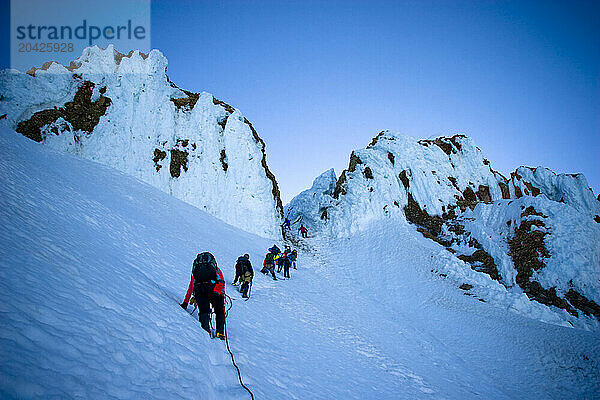 A large group of mountaineers ascend Mount Hood after the sun has set in Oregon.