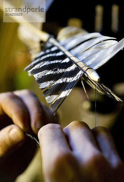 In his workshop in Lake Pleasant  Massachusetts  a craftsman wraps a turkey feather around an arrow shaft to create the fletching.