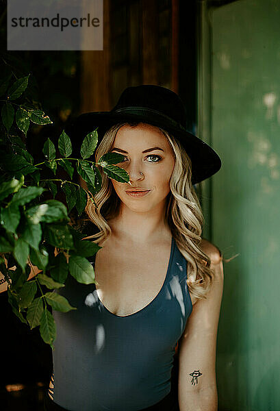 Playful grin behind leaves  stylish blonde in urban green