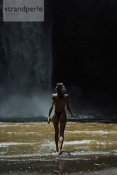 Woman traveler at the waterfall Nung Nung. Bali