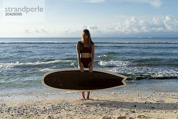 Young woman with surfboard on a beach.