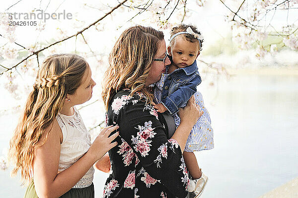 Woman holding a baby while another woman stands close  surrounde