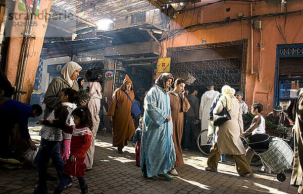 Pedestrians walk down a crowded paved street in Marrakech  Morocco  in North Africa.