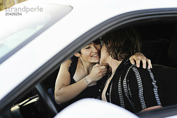 Couple sharing a tender moment inside a white car  smiling and c