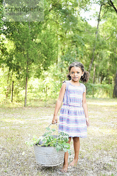 Girl holding a basket of harvested vegetables  standing outdoors