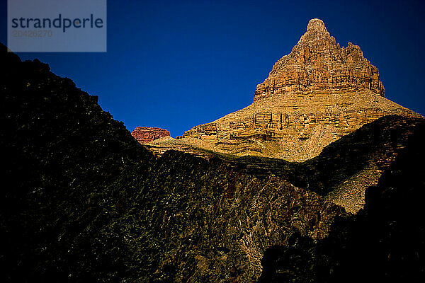 The sun sets on a rocky tower in Grand Canyon National Park in Arizona.