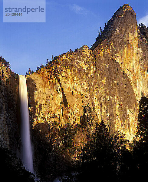 Sunset warming up the scene on Bridal Veil Falls and the Leaning Tower in Yosemite National Park  California.