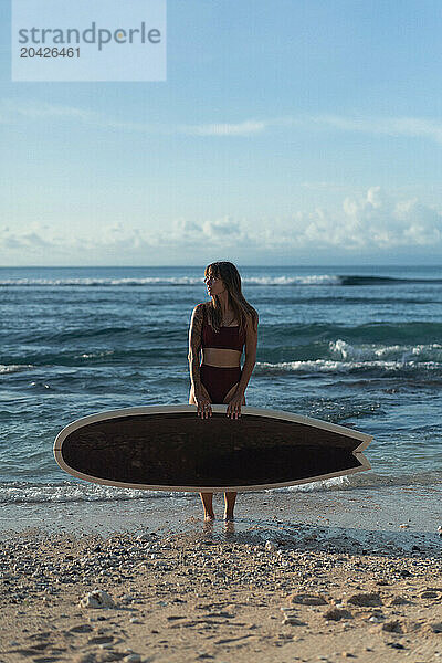 Young woman with surfboard on a beach.