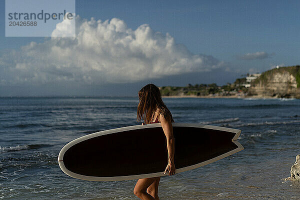 Young woman with surfboard on a beach.