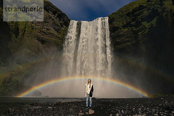 Woman standing in front of Skogarfoss waterfall in Iceland.