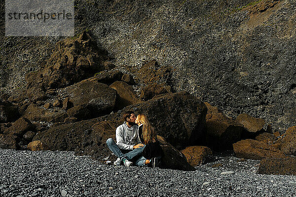 Couple kissing amidst basalt columns of the Reynisfjara beach.