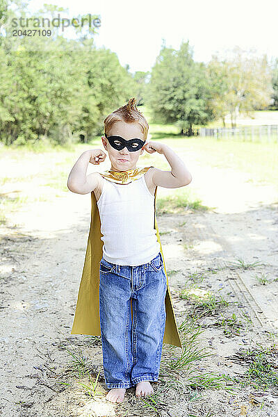 Toddler in superhero costume posing confidently outdoors.