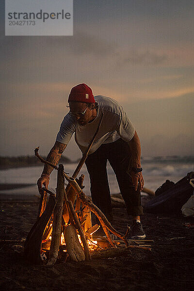 Man makes a bonfire on the beach.