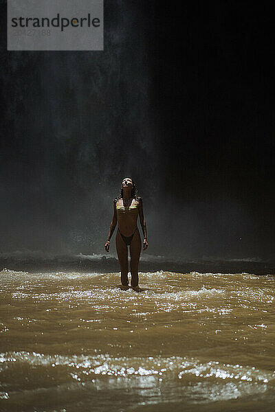 Woman enjoying under waterfall flowing over rock formation