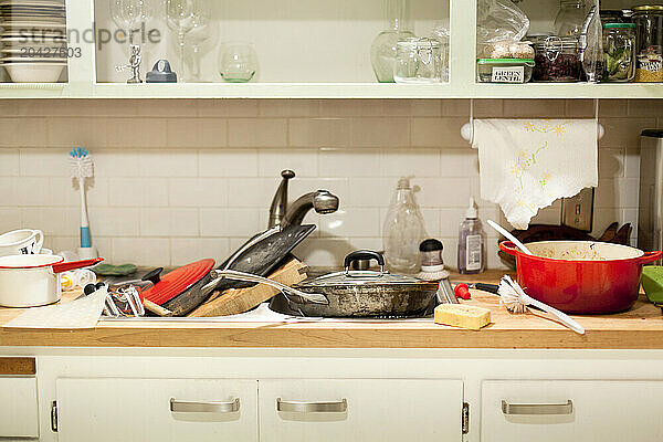 Piles of dirty pots and pans in a kitchen sink in a home.