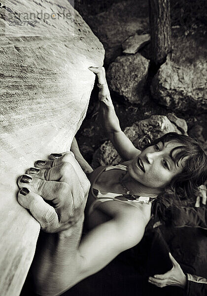 A yong woman pulls hard on a sloper hold while bouldering in Sedona  Arizona.