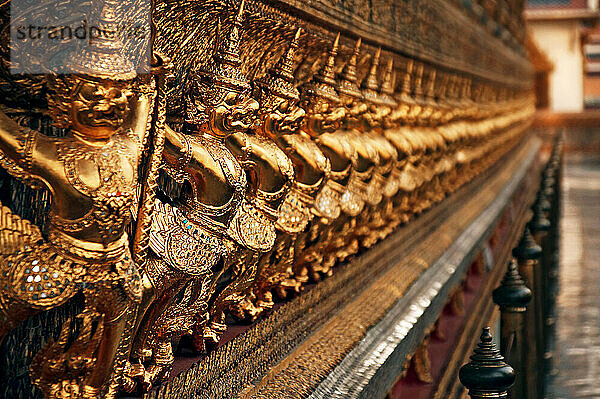 A band of gold Demons surrounding the Emerald Buddhas Temple  Wat Phra Kaeo  Royal Grand Palace  Bangkok  Thailand