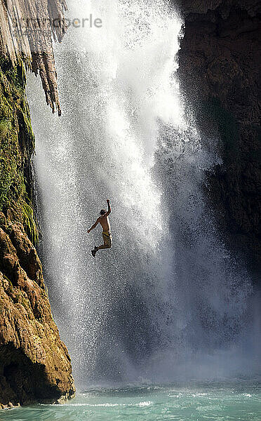 A man jumping into a waterfall at Havasu Falls  Grand Canyon Arizona