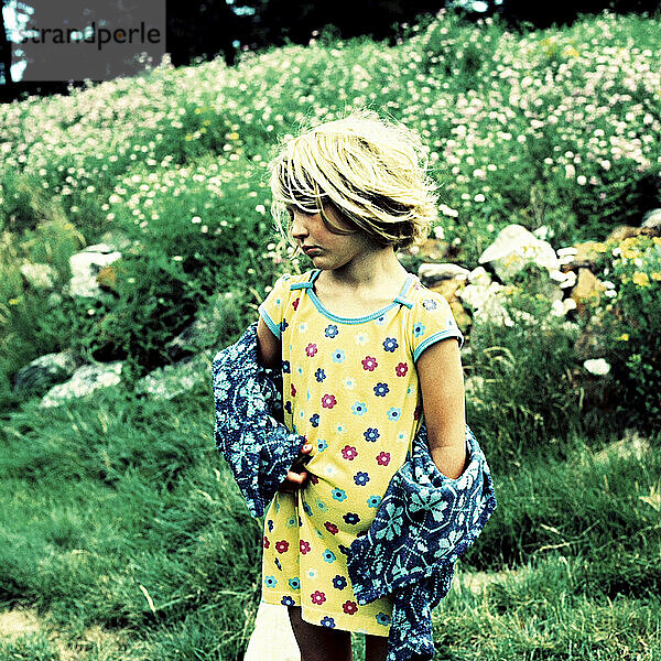 a young girl  still in her nightgown  stands in the grass on a maine summer morning