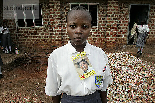 Young girl stands outside of a school in Uganda.