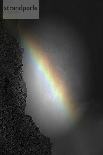 Brightly-colored rainbow set in a haze over Victoria Falls on Zambesi River .