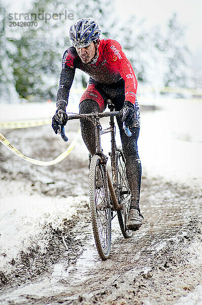 A cyclists races in the mud and snow at a Cyclocross race in Boulder  CO.