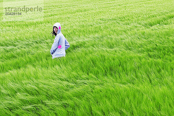 A young woman stands in a field  Berg  Switzerland.