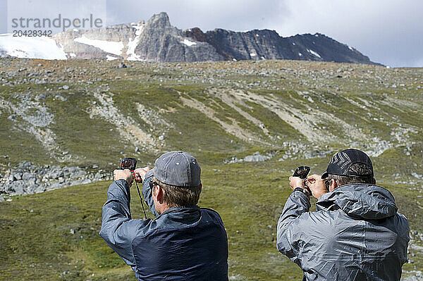 Two men using compasses on Jonas Pass in Jasper NP  Alberta  Canada.