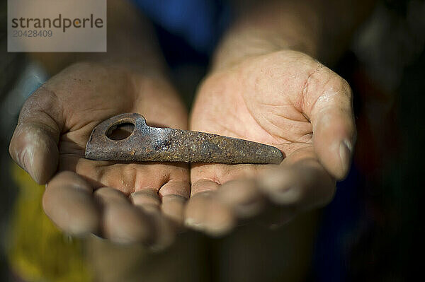 A close up of hands presenting an old piton