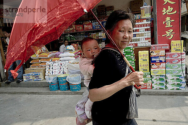 A grandmother carries her grandchild on her back.