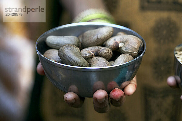 A hand holding a metal ball with cashew nuts.