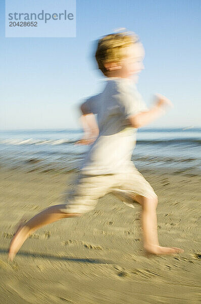 Young boy running fast down the beach.