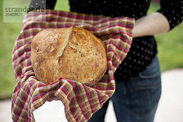 A young woman stands in her garden holding a loaf of homemade organic bread in Seattle  Washington.